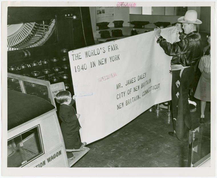 A man dressed as a cowboy studies a large letter in front of the massive typewriter. Photo Credit: New York Public Library/Retronaut
