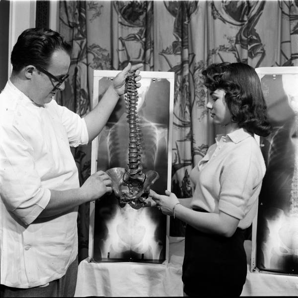 Lois Conway stands by her spinal X-ray and reviews a model of the human spine with a chiropractor. Photo Credit: Wallace Kirkland/LIFE